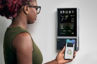 Frau bucht mit Smartphone ihre Arbeitszeiten am Zeiterfassungsterminal von PCS Systemtechnik.