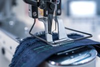 Nahaufnahme einer Nadel einer professionellen Nähmaschine beim Nähen auf Stoff, was die Präzision und Multifunktionalität von Kombi-Nähmaschinen in der Textilindustrie veranschaulicht. Nahaufnahme einer Nadel einer professionellen Nähmaschine beim Nähen auf Stoff, was die Präzision und Multifunktionalität von Kombi-Nähmaschinen in der Textilindustrie veranschaulicht.
