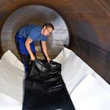 Today, it is very easy to convert a decommissioned steel tank into a rainwater storage tank using the AFRISO AR-SM, an inner lining with magnets. The picture shows the service technician standing on the bottom fleece layer and fitting the lining. The lining will soon be inflated like a balloon using a blower and the magnets will click into position at the tank wall exactly where planned