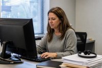 Mitarbeiterin eines mittelständischen Betriebs arbeitet mit einem Sprachassistenten am Rechner