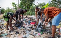 Four young adults collect garbage in an illegal open-air landfill in Africa