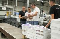 As one of the first print shops in Europe, Onlineprinters successfully certified its postpress operations. Armin Schörghofer (2nd from right), Ugra auditor, examines brochures in postpress together with co-auditor Thomas M. Schnitzler. (Bild: Onlineprinters GmbH)