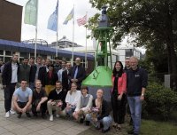 Studierende und Mitarbeitende der Nautik an der Hochschule Bremen freuen sich mit ihren Gästen über die neuen Seefahrttonnen an ihrem maritimen Standort am Campus Airbortstadt der HSB. Mit dabei: Kai Stührenberg, Staatsrat von Bremens Senatorin für Wirtschaft, Häfen und Transformation und Rektor Konrad Wolf (beide direkt links neben der grünen Tonne).