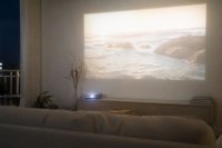 Projektor wirft ein Bild an die Wand eines abgedunkelten Wohnzimmers