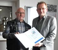 Rüdiger Loock, Fachkraft für Arbeitssicherheit der Frankenfeld Logistikgruppe (links im Bild), nimmt den Preis von Guido Stadtmann, BGHW, in Empfang