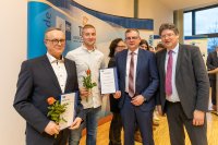 WEMAG-Personalleiter Michael Enigk und Facharbeiter Dennis Riemer nehmen von IHK-Präsident Matthias Belke und Wirtschaftsminister Reinhard Meyer (v. l.) die Urkunden entgegen. Foto: WEMAG/Stephan Rudolph-Kramer
