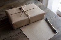 Eingepacktes Geschenk liegt neben einem Notizzettel auf dem Tisch