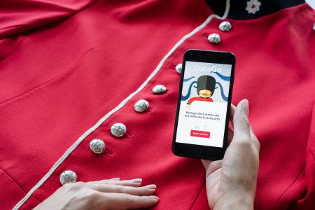 Hand spielt App DataDuell auf der Jacke eines Guards 2/2