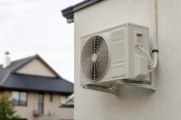 Außeneinheit einer Klimaanlage an einer verputzten Hauswand - Die Außeneinheit einer Klimaanlage hängt an einer hellen, verputzten Hauswand, daneben laufen isolierte Kältemittelleitungen nach unten, im Hintergrund unscharf ein Nachbargebäude. Symbolbild zu den neuen Vorgaben für Kältemittel in Raumklimageräten