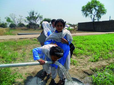 Pakistanische Mädchen an der Wasserpume