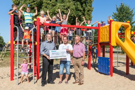 Im Rahmen der Wiedereinweihung des Kinderspielplatzes überreichte WEMAG-Kommunalbetreuer Bernd Halfkath (li.) den symbolischen Spendenscheck im Beisein des Bürgermeisters Jürgen Kühl (re.) an den stellvertretenden Vorsitzenden des Vereins Spielplatz-Freunde e.V. Suckow, Ronny Kleinke / Foto: WEMAG/Stephan Rudolph-Kramer