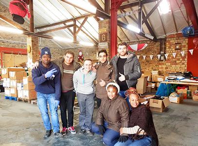 Gemeinsam mit Flüchtlingen helfen die Alpensped-Mitarbeiter Kenan Ramani und Jens Schnöde bei der Kleidersortierung im Benjamin-Franklin-Village.