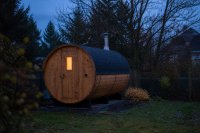 Freistehende Holzsauna im herbstlichen Garten bei Dämmerung