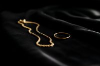 Feine Goldkette und ein Ring auf dunklem Samt