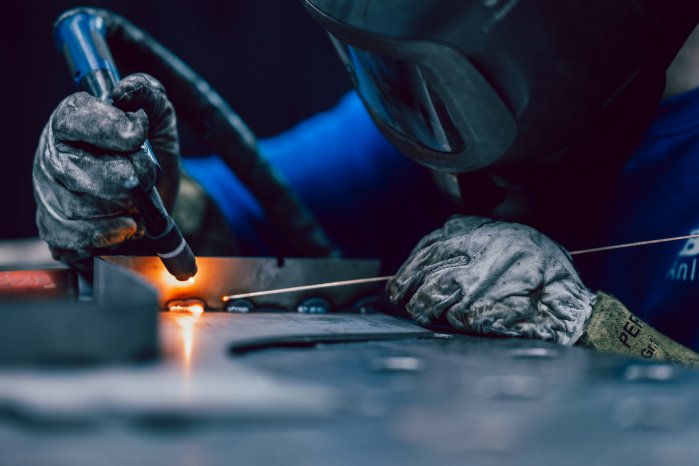 Metallbauer beim händischen Schweißen eines Bauteils.jpg