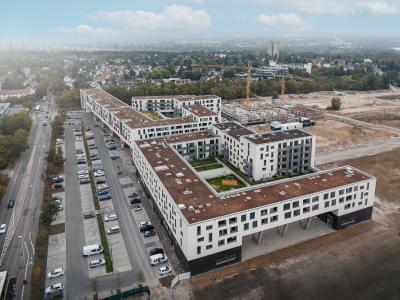 Blick auf das Quartierszentrum, das Herz des neuen Stadtviertels im Mainzer Stadtteil Weisenau. Das Gebäude überzeugt optisch mit luftigen V-Stützen und fungiert damit als Tor in das neue Quartier.
Bild: Hitzler Ingenieure