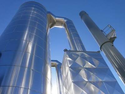 (left to right) One of the three boilers in vertical design with combustion air preheating to increase plant efficiency and the chimney. Each boiler has a net thermal capacity of 16.000 kW (16 MW)