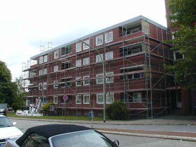 (Alte Fassade) Das Gebäude während der Sanierung: Die Klinkerverblendungen wurden in Teilen durch ein Wärmedämm-Verbundsystem ersetzt und anschließend verputzt.