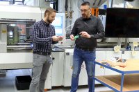 Christian Deubel, Senior Engineer Spritzgießen (links), und Dr. Michael Bosse, Gruppenleiter Materialentwicklung und -prüfung, diskutieren anhand der Porben von Positive Plastics Qualitätsmerkmale der Kunststoffe (Foto: SKZ)