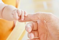 Hand eines Babys, das nach der Hand einer erwachsenen Person greift, © RitaE