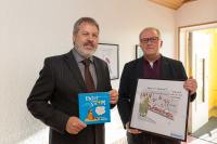 Der Amtsvorsteher Burkhard Thees (re.) hat mit WEMAG-Kommunalbetreuer Bernd Halfkath im Amt Dömitz-Malliß die Cartoon-Ausstellung 