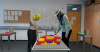 Zwei Personen, die sich an unterschiedlichen Orten befinden, bauen mit Hilfe des im Projekt Co-Humanics entwickelten Augmented Reality-Systems gemeinsam ein virtuelles Haus aus Legosteinen