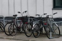 Abgestellte Fahrräder an einem Ständer vor einer Hauswand. Mehrere Fahrräder stehen dicht nebeneinander in einem Fahrradständer vor einer schlichten Hauswand. Symbolbild zum deutschen Fahrradmarkt.