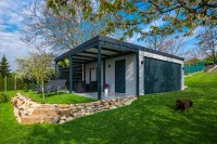 Individuell geplante Fertiggarage von GARDEON mit überdachtem Sitzbereich. Die gedämmte Stahlpaneel-Konstruktion bietet hohe Energieeffizienz, moderne Optik und flexible Nutzungsmöglichkeiten: von Garage über Stauraum bis zum Hobbyraum.