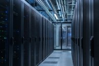 Kaltgang eines Rechenzentrums mit geschlossenen Serverschränken, Kabeltrassen und Klimaleitungen unter der Decke. Ein Kaltgang in einem Rechenzentrum: Reihen geschlossener Serverschränke mit blinkenden Statusleuchten, darüber Kabeltrassen und Kühlleitungen, am Ende des Gangs eine Glastür mit Sicherheitsschleuse, kühles Licht. Symbolbild zur Energieverbrauchseffektivität von Rechenzentren.