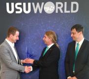 USU Geschäftsführer Sven Kolb (links) überreicht den Preis an Björn Feber (Technischer Service) und Stefan Ridinger von der IT (rechts)