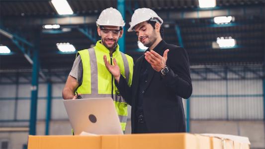 Zwei Arbeiter in einer Produktion diskutieren und arbeiten in einer Halle
