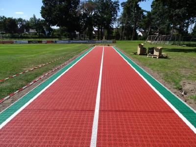 Als Oberbelag wurde ein perforierter Hart-Kunststoffbelag, aus UV- und witterungsbeständigem Polypropylen (PP) Kunststoff, in den Farben Ziegelrot und Grasgrün ausgewählt und schwimmend verlegt.