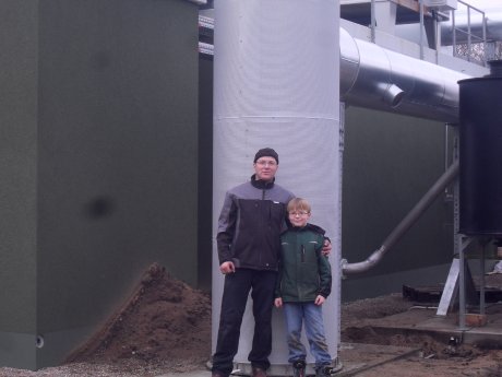 Jan Kroll mit seinem Sohn vor der Biogas-Anlage, die der Unternehmen der e2m zur Vermarktun.JPG