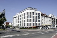 Gerundete Ecken und effektvoll gegliederte Geschosse: An der Kreuzung Würzburger Straße/Kurmainzer Ring belebt Unerwartetes die funktionale Tristesse. Foto: Caparol Farben Lacke Bautenschutz / Alexandra Lechner