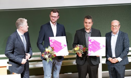 (Foto: Thomas Schmitt)
Eingerahmt von Laudator Stephan Hoffmann (l.) und Prof. Dr. Thomas Seul: Die überglücklichen Preisträger Julian Gundelwein (2. v. l.) und Samuel Werner halten stolz die Auszeichnung ihrer studentischen Leistungen in der Hand.