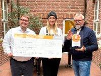 Nele Marschner, verantwortlich für die Öffentlichkeitsarbeit der WEMACOM, übergibt den symbolischen Spendenscheck und das Breitbandsiegel in Gold an den stellvertretenden Bürgermeister Lars Warne (links) und den ehemaligen Breitbandkoordinator Rüdiger Falk. Foto: WEMACOM/Cornelia Lindberg