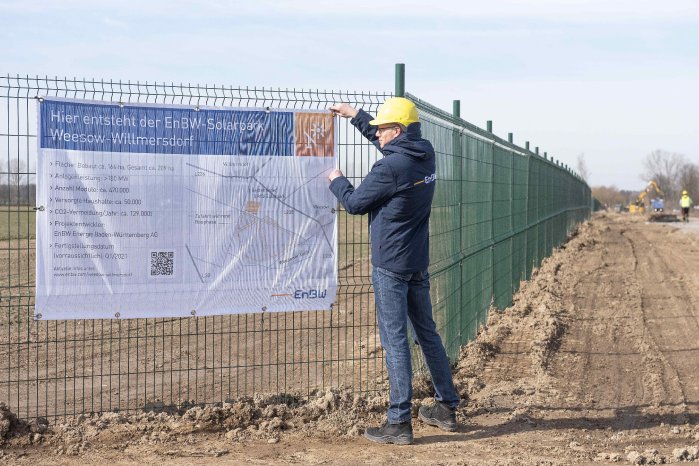 EnBW Mitarbeiter Michael Matthes befestigt das Bauschild vor Ort_KLE_5237 a.jpg