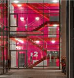 In der Abenddämmerung verleiht die Beleuchtung den roten und purpurfarbenen mit Amphibolin beschichteten Flächen in diesem Treppenhaus einen besonderen Charakter mit hohem Aufmerksamkeitswert