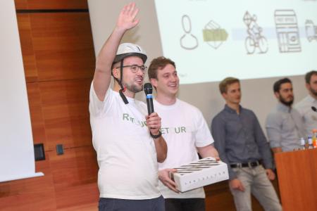Die Studierenden David Heid (links) und Robin Bässler (rechts) präsentieren ihre Idee „Retouro – Wir erledigen Ihre Retoure: SMART und GRÜN!“ beim Ideenwettbewerb „stAArt-UP!de Challenge 2018“, © Hochschule Aalen / Peter Schlipf
