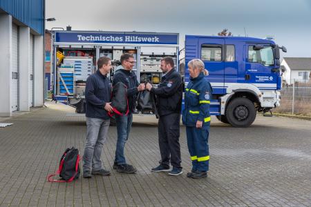 Die WEMAG-Mitarbeiter Remo Groß und Thoralf Taft überreichen dem THW-Zugführer Peter Burmeister-Schröder und Nicole Taft von der THW-Bergungsgruppe (v.l.) neun spezielle Schutzausrüstungen (Foto: WEMAG/Stephan Rudolph-Kramer)