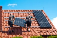 Handwerker montieren Solaranlage auf Einfamilienhaus.
