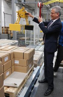 Beim Rundgang legte der hessische Wirtschaftsminister auch selbst Hand an und brachte an einer Hebevorrichtung ein Paket auf den Weg zu Rittal Kunden. Quelle Rittal GmbH & Co. KG