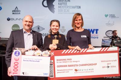 Herzlichen Glückwunsch! Dr. Frank Neuhausen (BWT water+more, l.) und Melanie Hansmeier (Deutscher Kaffeeverband, r.) gratulieren der deutschen Barista-Meisterin 2016 Chloe Natrass (Mitte) zu ihrem Sieg. /Foto: Sinan Muslu
