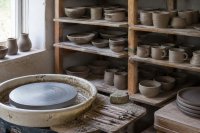 Töpferwerkstatt mit ungebrannten Gefäßen auf einem Holzregal