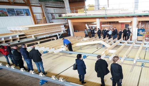 tectofix 3000 in Aktion: Bei der dritten Produktionsbesichtigung in diesem Jahr nutzten Interessenten aus 20 Firmen die Gelegenheit, bei Bauer Holzbau in Satteldorf-Gröningen die Produktion einer Dachhälfte mit Querbaukehle auf der Vorfertigungsanlage tectofix 3000 live mitzuerleben. Foto: Bauer Holzbau, Satteldorf; www.bauer-holzbau.de