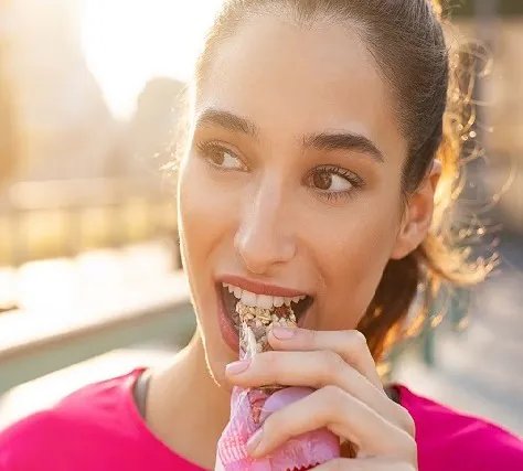 sporty-woman-eating-energy-bar-474x427-1.webp